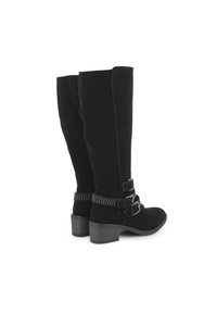 Botas de ante negras hasta la rodilla con tacón cuadrado, que cuentan con dos correas ajustables adornadas con tachuelas plateadas en el tobillo.