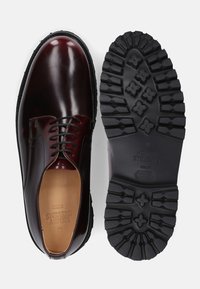 Burgundyleder-Schuhe mit glänzender Oberfläche, ausgestattet mit einem klassischen Schnürdesign und einer schwarzen Gummisohle mit robustem Profil.