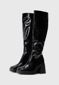Black knee-high boots with a glossy finish, square toe, and a chunky heel. Includes a side zipper and smooth texture.
