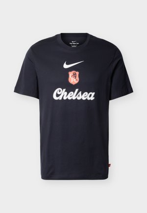 Melna Nike T-krekls ar baltu Nike logotipu, sarkanu Chelsea FC emblēmu un baltā skriptā uzrakstu "Chelsea" priekšpusē.
