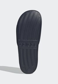 Semelle en caoutchouc noir avec un motif de traction en zigzag ; logo "adidas" en relief ; texture lisse ; bord de talon arrondi.