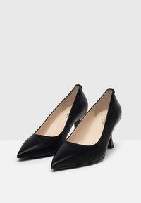 Czarne skórzane buty na wysokim obcasie z wydłużonym noskiem i trójkątnym obcasem. Gładka tekstura, minimalistyczny design i jasnobeżowa wkładka.