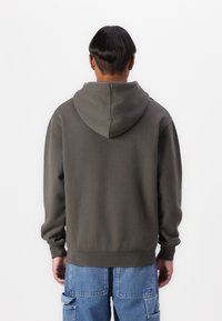 Hooded sweatshirt in dark gray cotton fabric. Features a relaxed fit, ribbed cuffs, and a plain design with no visible patterns or accents.