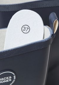 Cizme impermeabile bleu închis cu talpă albă marcată mărimea 37, prevăzute cu buclă de tragere și logo Jack & Jones pe partea exterioară.