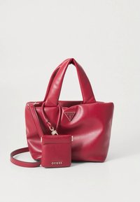 Sac à main en cuir synthétique rouge avec deux anses, un petit porte-monnaie amovible et un accent de logo triangulaire. Texture lisse et forme rectangulaire.