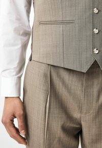 Grå mønstret vest med en enkelt brystlomme og seks knapper, parret med lysegrå plisserede bukser. Hvide skjorte-manchetter synlige.
