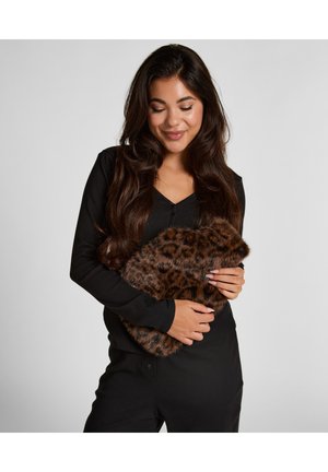Clutch en fausse fourrure à motif léopard brun tenue devant une personne, présentant une texture douce et une forme arrondie, sur un fond neutre.