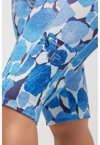 Pantalones cortos deportivos de color azul con un patrón que presenta distintas tonalidades de azul y blanco, con un pequeño bolsillo con cremallera y un detalle de logo en el muslo.