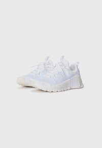 Baskets de sport blanches avec une tige en textile, bout rond, semelle texturée et lacets. Elles offrent un coussinage doux et un détail de logo discret.