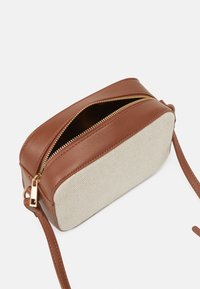 Borsa a tracolla in pelle marrone e tessuto intrecciato beige con zip dorata, forma ovale e cinturino regolabile. Cuciture visibili e accessori in evidenza.