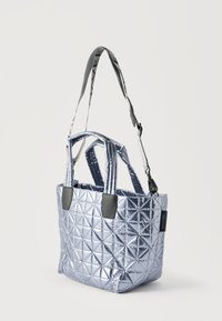 Τσάντα tote ασημί μεταλλικό με ραμμένη γεωμετρική υφή, δύο κοντές λαβές και ένα ρυθμιζόμενο μακρύ λουράκι, με πλαϊνή ετικέτα λογότυπου.