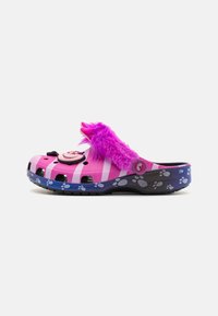 Roze Crocs met een zwart-wit gestreept ontwerp, voorzien van een paarse fluffy band, pootafdrukaccenten en een decoratieve knop aan de voorkant.