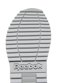 Semelle de sneaker en caoutchouc gris avec des motifs de grip texturés et un logo Reebok bien en évidence. La conception épaisse et striée améliore l'adhérence.