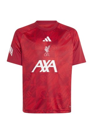 Junge trägt rotes Liverpool FC-Trikot und schwarze Adidas-Hose, hält einen schwarz-weißen Fußball, lächelt, steht vor weißem Hintergrund.