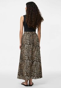 Maksi kleita ar melnu pieguļošu augšu un leopardu raksta svārkiem, ar elastīgu jostu un plūstošu audumu. Valkāta ar plakaniem zābakiem.