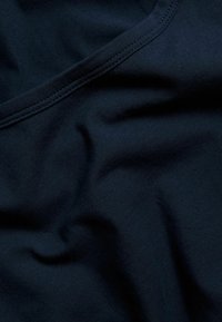 Dunkelnavyfarbener Stoff mit glatter Textur, der feine Falten und einen runden Halsausschnitt zeigt, mit zarten Nähten entlang der Kanten.