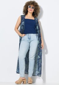 Námořnický top, dlouhý kimono s modrým vzorem, světle modré džíny a béžové platformové sandály. Model má na sobě oversized sluneční brýle a kroužkové náušnice.