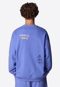 Sudadera de algodón morada con el texto "EXPLORERS GATHER" en una fuente colorida en la parte posterior y un gráfico de una furgoneta de dibujos animados azul con detalles.