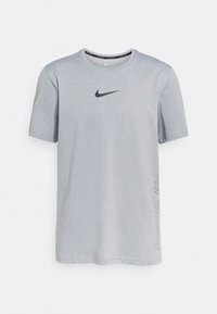 Camiseta de manga corta gris claro hecha de una tela suave. Presenta un logotipo de Nike negro en el pecho y el texto "NIKE DRY" impreso a lo largo del costado.