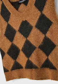 Gilet sans manches en laine marron et noire duveteuse avec un grand motif losange argyle et un col en V ainsi qu’un ourlet côtelé.