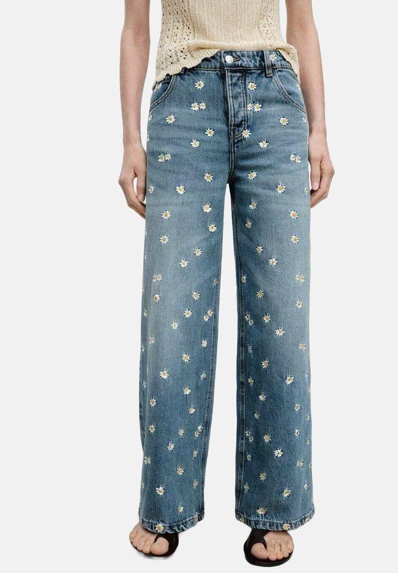 Ljusblå denim byxor med vida ben och broderier av gula och vita prästkragar, med en standard femfickorsdesign och en avslappnad passform.