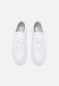White sneakers made of smooth leather with a rounded toe, flat laces, and a subtle logo on the side; lightweight rubber sole.