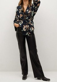 Blouse à motifs floraux dans les tons marine avec des accents cr ème et aqua, associée à un pantalon large en simili cuir noir et des escarpins à bout carré.