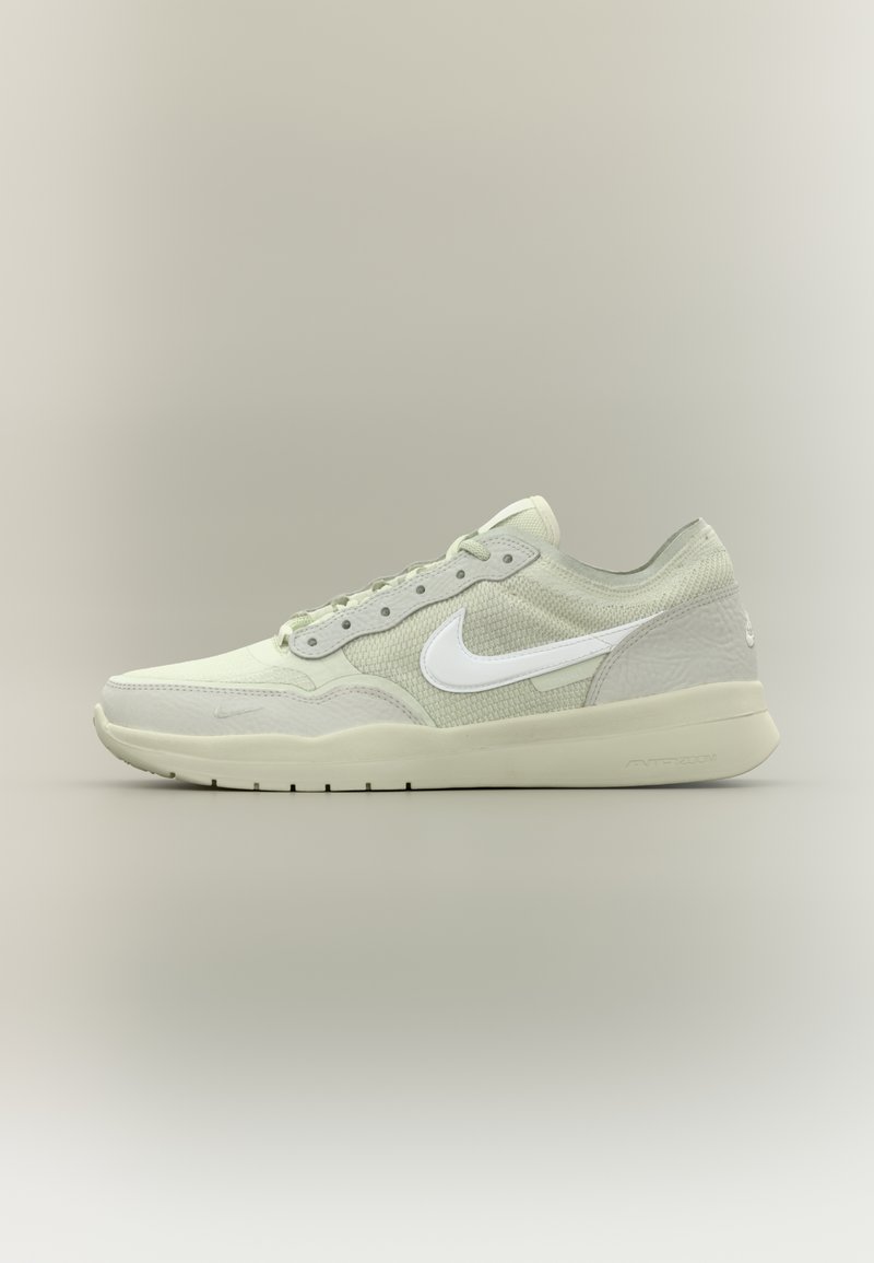 Heleroheline sportlik king, millel on tekstuuriga võrgust pealiskonstruktsioon, valge Nike tähis, tooniton paelad ja paks tald, millel on peen muster.