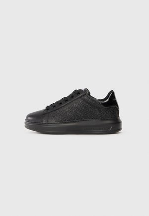 Schwarze Sneakers mit einer strukturierten Oberseite, die ein wiederkehrendes Logomuster zeigt, flacher Schnürverschluss und eine robuste Gummisohle.