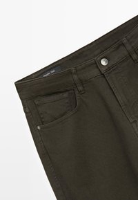 Donkergroene denim broek met voorzak, muntzak, riemlussen en metalen knoopsluiting.