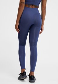Marina träningsleggings med texturerad design, hög midja och kontrasterande randiga detaljer. Matchas med svarta träningsskor.