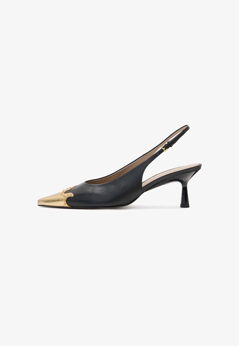 Sapato slingback em pele preta com bico afunilado, ponteira metálica dourada e pequeno salto preto brilhante; apresenta tachas decorativas na parte da frente.