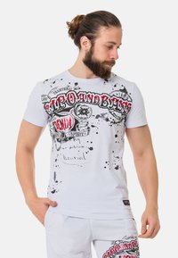 Witte katoenen T-shirt met zwart en rode grafische prints met spetters. Korte mouwen en een ronde halslijn.