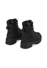 Stivali alla caviglia in suede nero con punta arrotondata, chiusura con lacci davanti e suola chunky con texture. Finiture in pelle nera sul colletto e sul tallone.