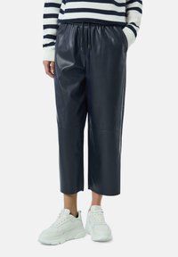 Navy faux skórzane spodnie  cropped z elastycznym pasem, bocznymi kieszeniami i płaskimi szwami, zestawione z masywnymi białymi sneakersami.