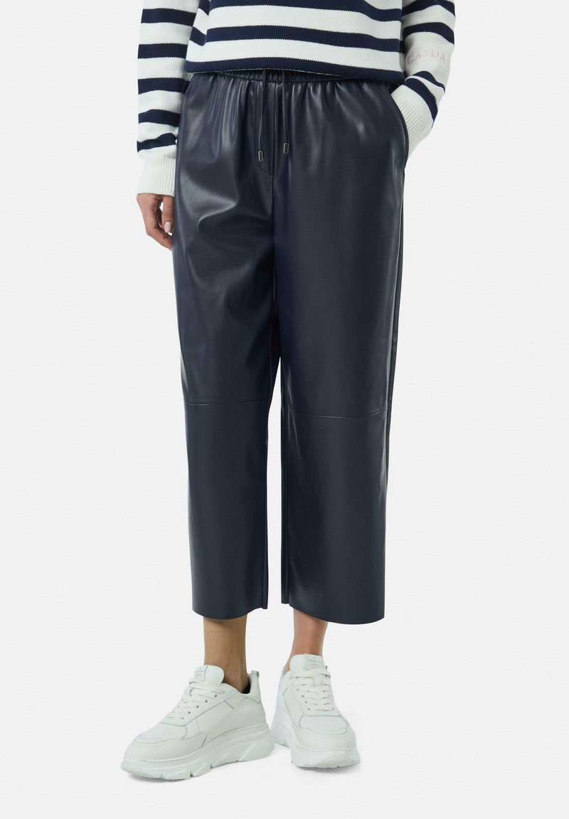 Marineblauwe nepleren cropped broek met een elastische tailleband, zijzakken en platte naden, gecombineerd met stevige witte sneakers.