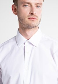 Witte button-up shirt met een klassieke kraag, glad katoenweefsel en een subtiele glans. Voorzien van vijf knopen en een getailleerde pasvorm.