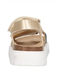 Back view of a sandal featuring a light beige leather upper, cork footbed, and a white rubber sole. Straps are adjustable.