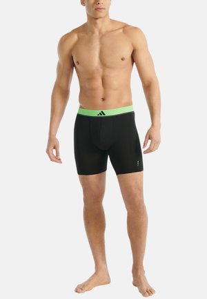 Zwarte boxershorts met een groene elastische tailleband, versierd met een gestreept textuurpatroon en merknaam. Gemaakt van stretchstof voor extra comfort.