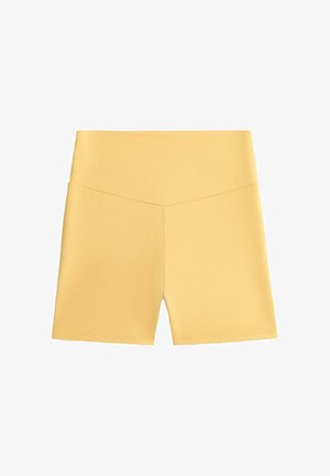 Žute biciklističke hlače visokog struka s V-oblika šavom sprijeda i glatkim, pristajućim dizajnom tkanine.