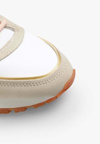 Zapatilla deportiva con parte superior de cuero blanco, superposiciones de ante beige y acentos dorados. Cuenta con una suela texturizada, punta redondeada y costuras reforzadas.