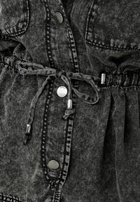 Črna oprana denim jakna z gumbom na pritisek, vrvico v pasu in žepi na ramenih za strukturiran, a sproščen videz.