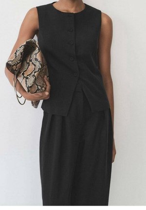 Haut sans manches noir avec cinq boutons et une coupe ajustée, associé à un pantalon noir ample et une pochette beige et noire à motifs.