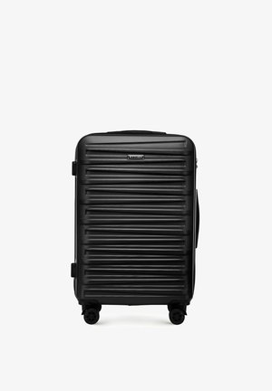 Valise rigide noire avec des rainures horizontales texturées, une poignée supérieure et quatre roues pivotantes pour une maniabilité facile.