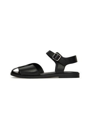 Sandali in pelle nera con design a punta aperta, cinturino alla caviglia con fibbia e suola piatta per il massimo comfort.