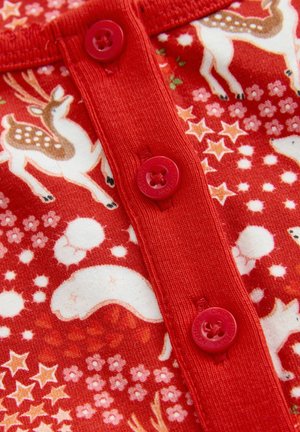 Dettaglio ravvicinato di un tessuto rosso con bottoni rossi, decorato con orsi bianchi, renne, stelle arancioni e fiori in un motivo festivo.