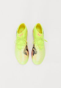 Botas de fútbol en amarillo neón con acentos negros, superficie texturizada y cordones a juego. Presentan un diseño ceñido para un mejor rendimiento.