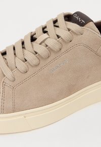 Tenis bej din suede, cu șireți din textil, talpă din cauciuc și un accent din piele maro la călcâi, cu logo-ul mărcii embosat.