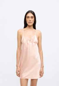 Νυχτικό από σατέν σε απαλό ροζ, με λεπτές τιράντες, δαντελένιες λεπτομέρειες στο μπούστο και ελαφρώς άνετη εφαρμογή στο μήκος έως το μέσο του μηρού.