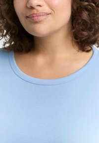 Lichtblauw shirt met korte mouwen en een ronde hals, gemaakt van zachte, gladde stof, met een naadloos ontwerp en minimale stikdetails.
